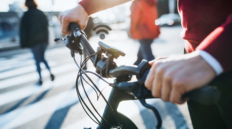 A midsection of businessman commuter with electric bicycle traveling to work in city.