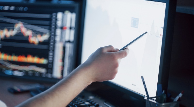 Analyzing data. Close-up of young businessman pointing on the data presented in the chart with pen while working in creative office
